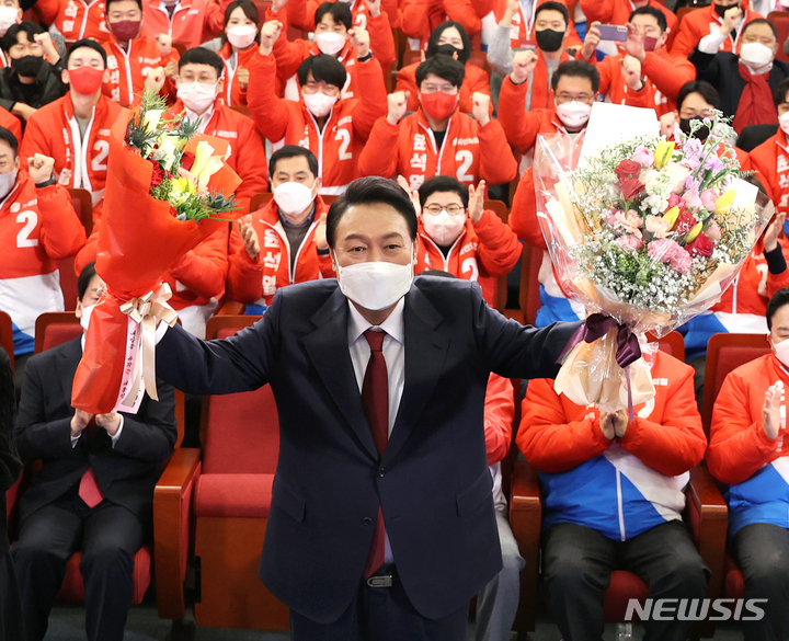 윤석열 제20대 대통령 당선인이 10일 새벽 서울 여의도 국회도서관에 마련된 국민의힘 제20대 대통령선거 개표상황실에서 꽃다발을 들고 있다. (뉴시스 제공, 공동취재사진)