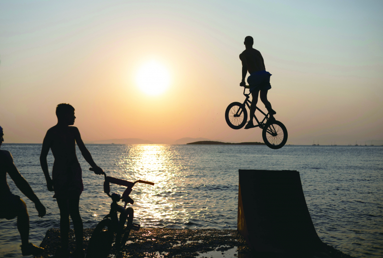 19일(현지 시간) 그리스 아테네 남쪽 카부리 해변에서 청소년 한 명이 BMX 자전거를 타고 무더위 속 바다로 뛰어들고 있다. 뉴시스
