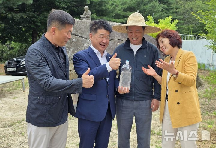 왕두꺼비 산장 식당 마당에 있는 두꺼비 바위 앞에서 금율약수를 들고 기념사진을 찍는 배형태(왼쪽부터) 김천시의원, 나영민 김천시의장, 신승우 대표. 김응숙 김천시의원.